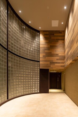 Un intérieur moderne avec un mur incurvé en verre, un plafond recouvert de panneaux en bois et un sol carrelé.