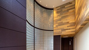 Een modern interieur met een gebogen glazen wand, een plafond van houten panelen en een betegelde vloer.