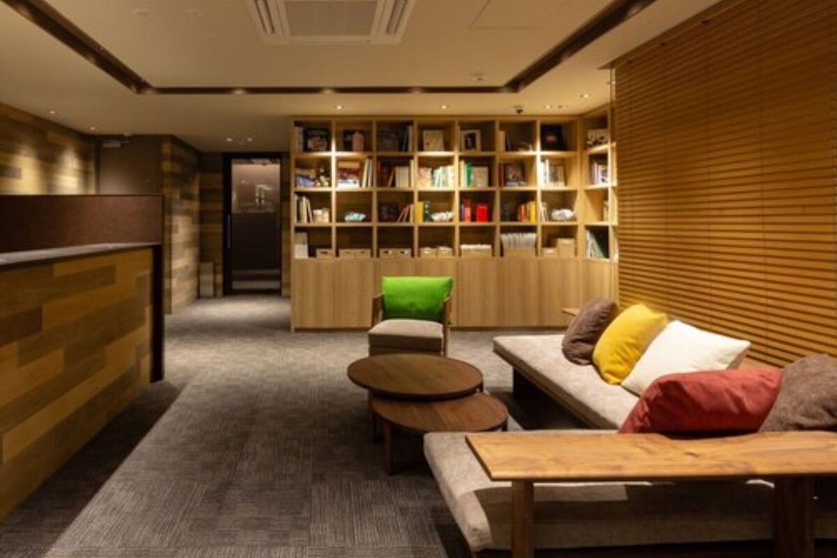 A reception area with a counter, a sofa, a small table, and a bookshelf filled with books.