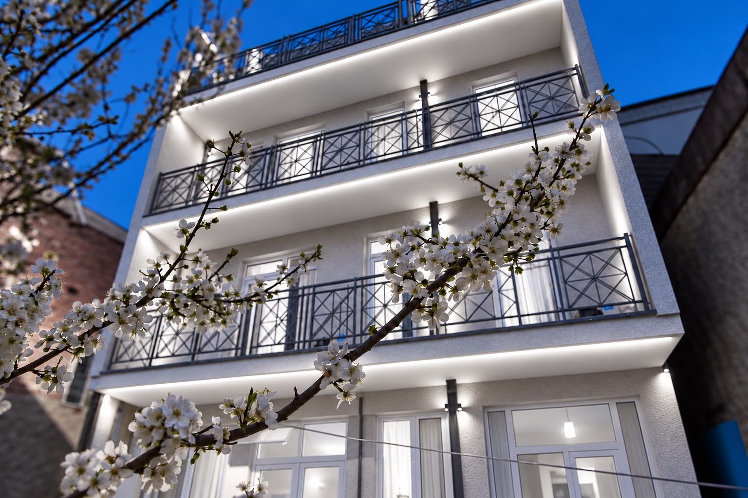 Un edificio de varios pisos con balcones y una rama de flores blancas en primer plano.