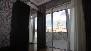 A room with a large sliding glass door leading to a courtyard with a view of a historic building. - Marialuis Hotel (Tbilisi)