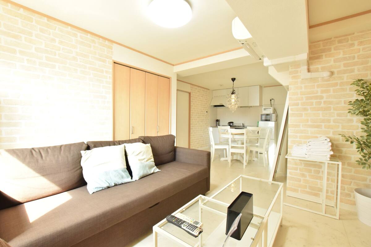 Una sala de estar moderna con un sofá marrón, una mesa de centro de vidrio y un control remoto.