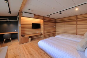 A modern bedroom with a bed, a desk, and a TV.