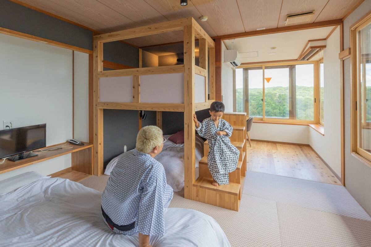 A room with a bunk bed, a television, and a large window.