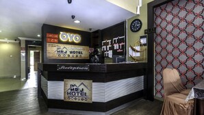 A hotel reception desk with a clock, a sign for the reception, and a wall with a geometric pattern. - OYO 717 MR J Hotel Wakaf Che Yeh 2 (Kota Bharu)
