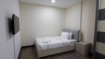 A bedroom with a bed, bedside table, and a TV mounted on the wall.