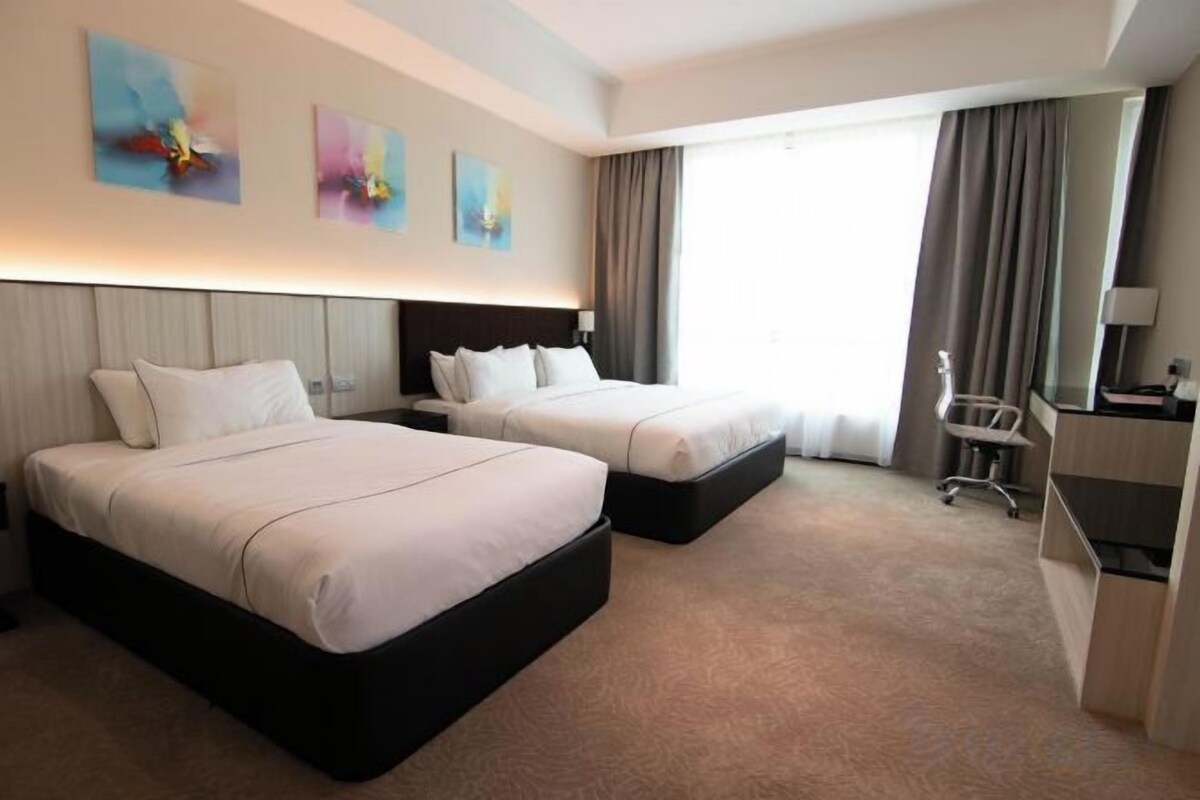 A hotel room with two beds, a desk, and a chair.