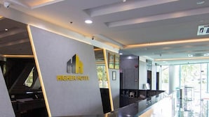 A reception desk with a modern design, a logo, and a glass partition. - Higher Hotel (Bandar Seri Begawan)