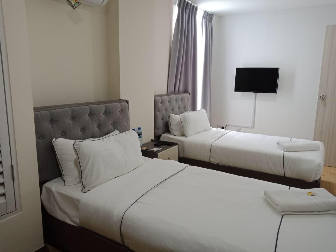 Une chambre d’hôtel avec deux lits, un téléviseur à écran plat et une fenêtre avec des rideaux.