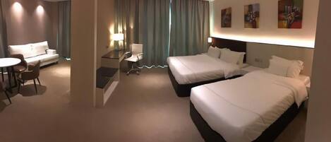 Una habitación de hotel con dos camas, un sofá, un escritorio y una silla.