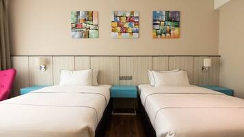 A hotel room with two beds, a headboard, and three paintings on the wall.