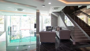A lobby with a staircase, seating area, and a glass entrance. - Higher Hotel (Bandar Seri Begawan)