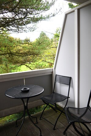 A balcony with a round table and two chairs, overlooking a green landscape. - Hotel & Pension Dat greune Eck (Soltau)