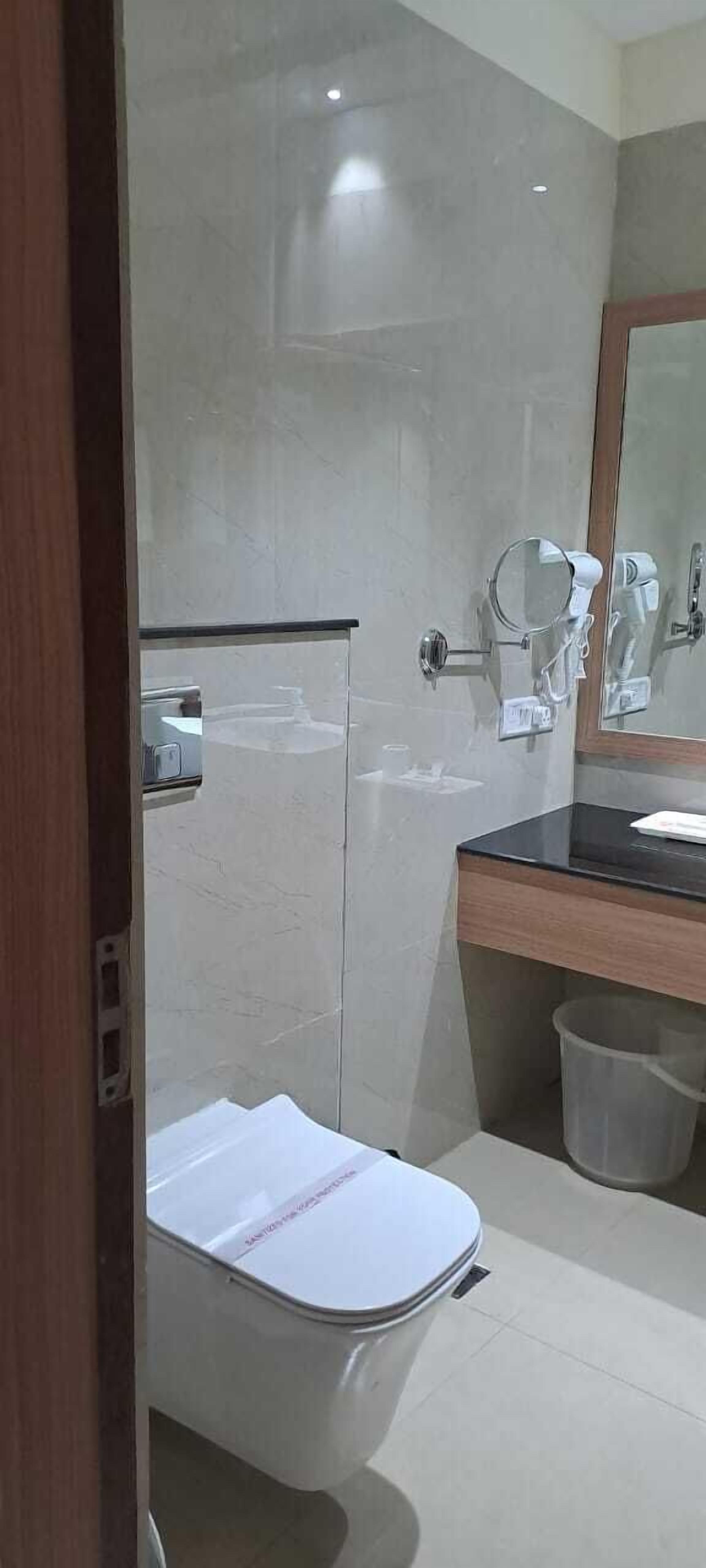 Un baño moderno con inodoro, lavamanos y espejo.