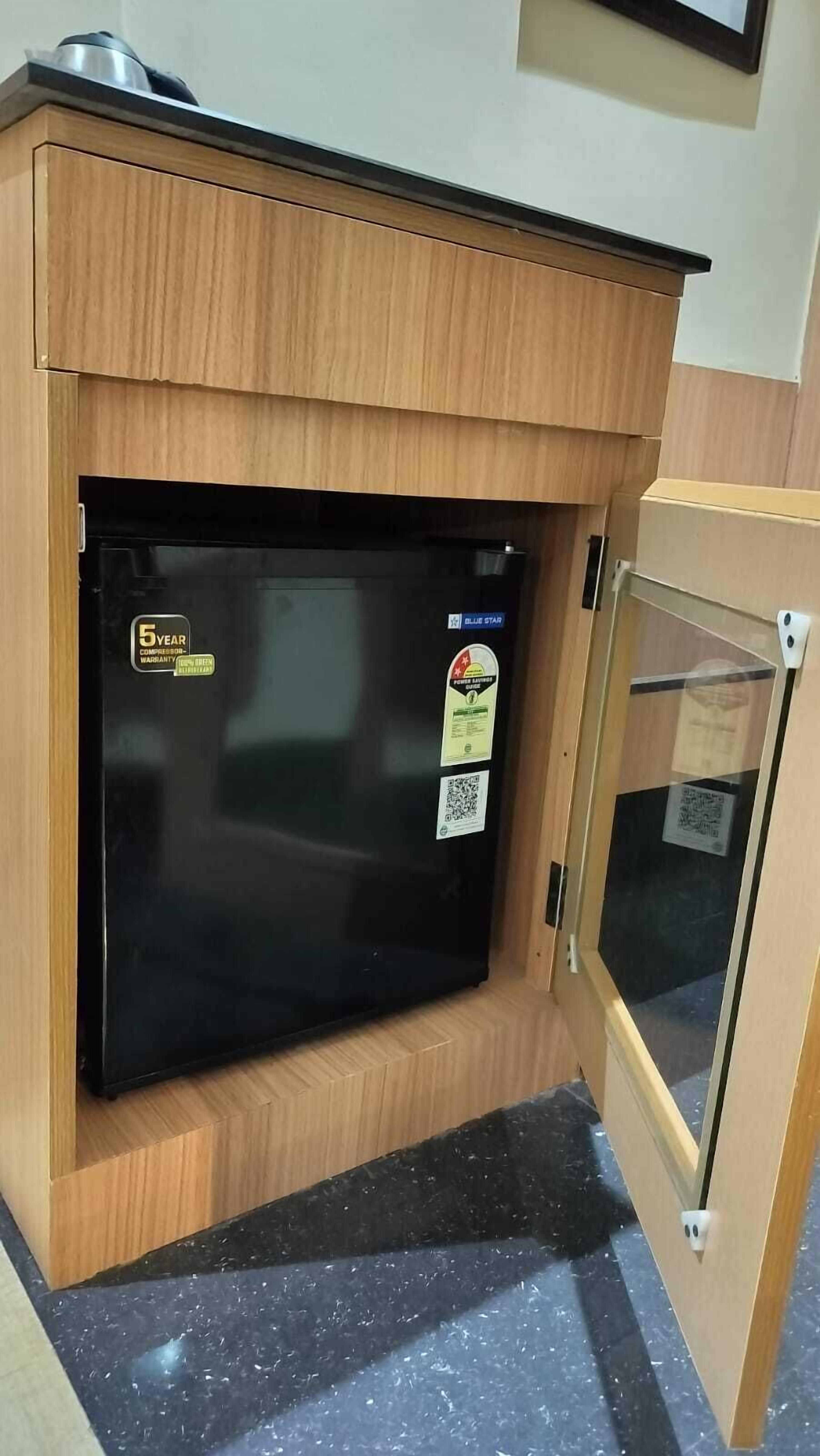 A compact refrigerator with a black exterior, a 5-year compressor warranty sticker, and a blue star certification label.