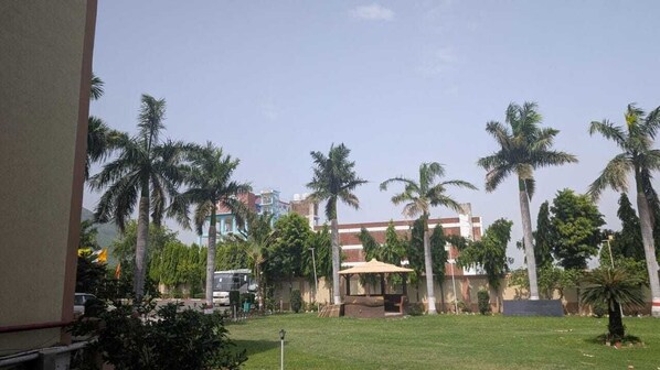 A courtyard with palm trees, a covered seating area, and a building in the background. - The Rajgir Residency (Rajgir)