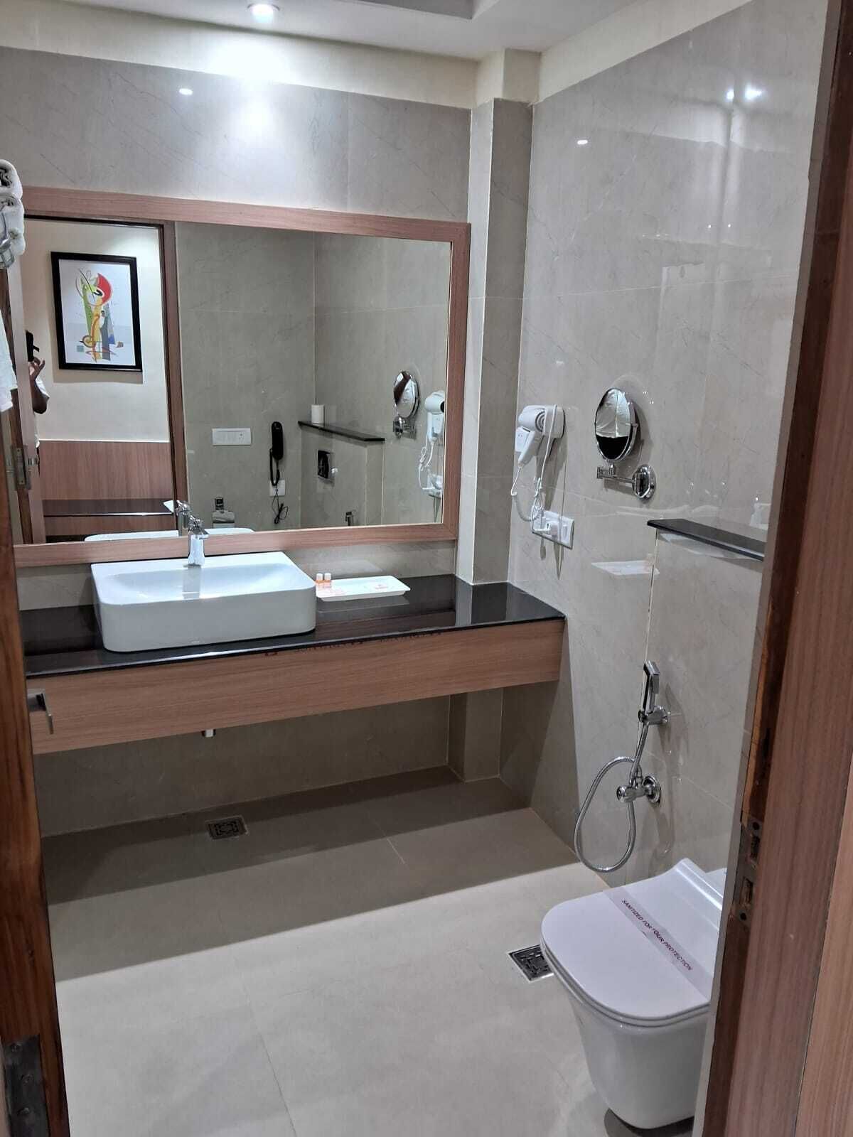 Un baño moderno con un espejo grande, un lavamanos y un inodoro.