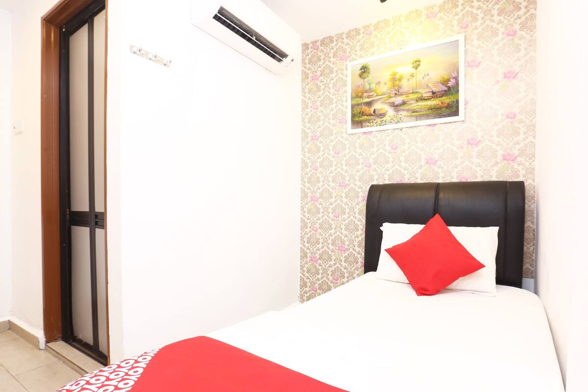 Une chambre d’hôtel avec un lit, une porte, un appareil de climatisation et un mur orné d’un motif floral.