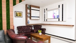 A modern living room with a leather sofa, a wooden coffee table, and a TV mounted on the wall. - OYO 718 MR J Hotel Wakaf Che Yeh 1 (Kota Bharu)