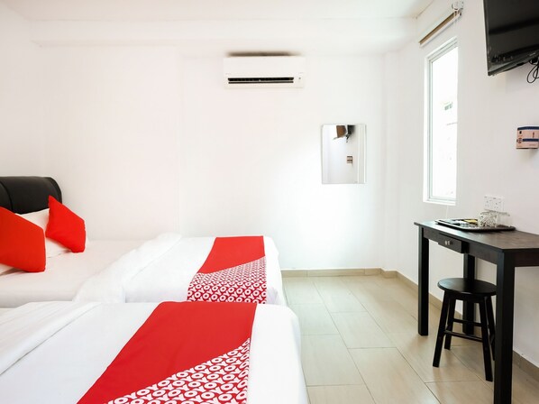 Une chambre d’hôtel avec deux lits, un bureau et une fenêtre.
