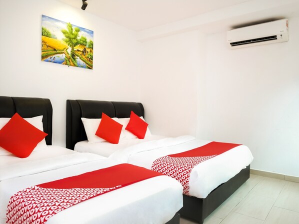 Ein Hotelzimmer mit zwei Betten, jeweils mit weißer Bettwäsche und roten Akzenten, einem Bild an der Wand und einer Klimaanlage.