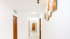 A corridor with doors on both sides, a sign indicating 'KELUAR', and artwork on the right wall. - OYO 718 MR J Hotel Wakaf Che Yeh 1 (Kota Bharu)