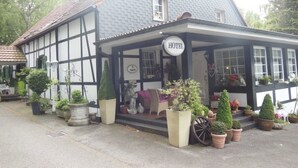 A traditional half-timbered hotel with a signboard, potted plants, and a covered entrance. - Hotel Kämpgens - Hof (Muelheim an der Ruhr)
