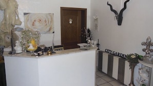 A reception area with a statue, a clock, and a flower arrangement. - Hotel Kämpgens - Hof (Muelheim an der Ruhr)