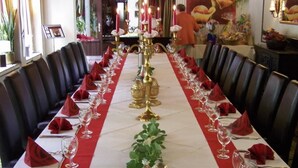 A long dining table with red napkins, wine glasses, and golden candle holders. - Hotel Kämpgens - Hof (Muelheim an der Ruhr)