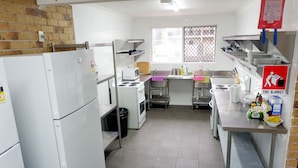 A kitchen with white appliances, a window, and a fire blanket sign. - Fantasy Ocean Holiday House (Coffs Harbour)