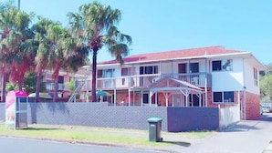 A two-story building with a red-tiled roof, a balcony, and a staircase leading to the upper floor. - Fantasy Ocean Holiday House (Coffs Harbour)