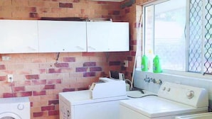 A laundry room with a washing machine, dryer, and sink. - Fantasy Ocean Holiday House (Coffs Harbour)