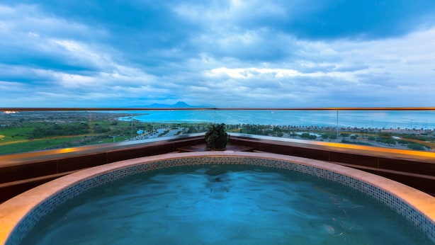 Una piscina con vistas a una amplia masa de agua y montañas distantes.