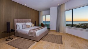 Un dormitorio moderno con una cama grande, un escritorio y vistas al mar.