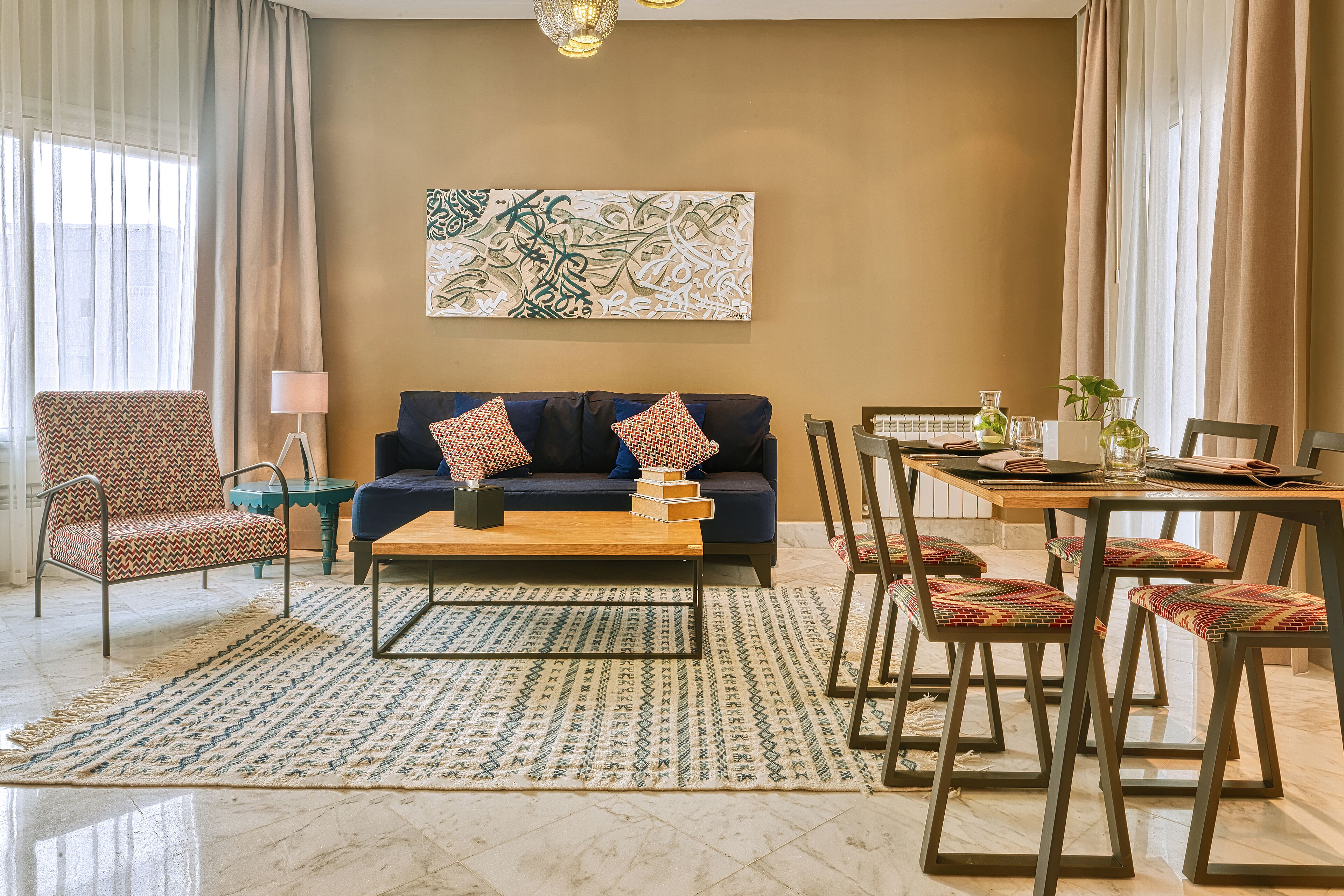 Ein Wohnzimmer mit einer Couch, Sesseln, einem Couchtisch und einem Esstisch mit Stühlen.