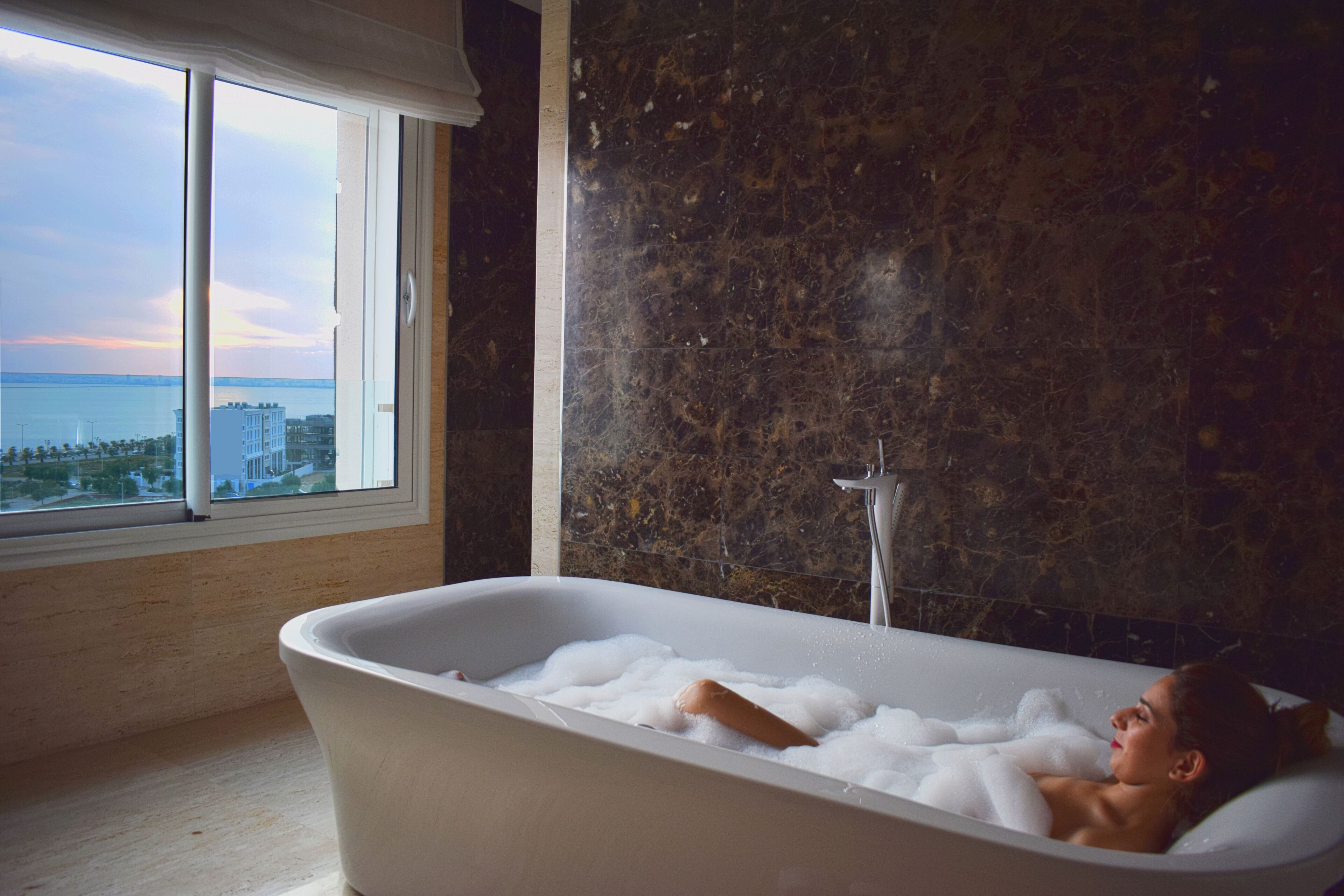A bathtub with a view of the sea through a large window.