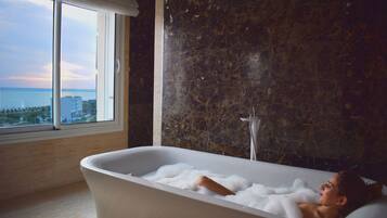 A bathtub with a view of the sea through a large window.
