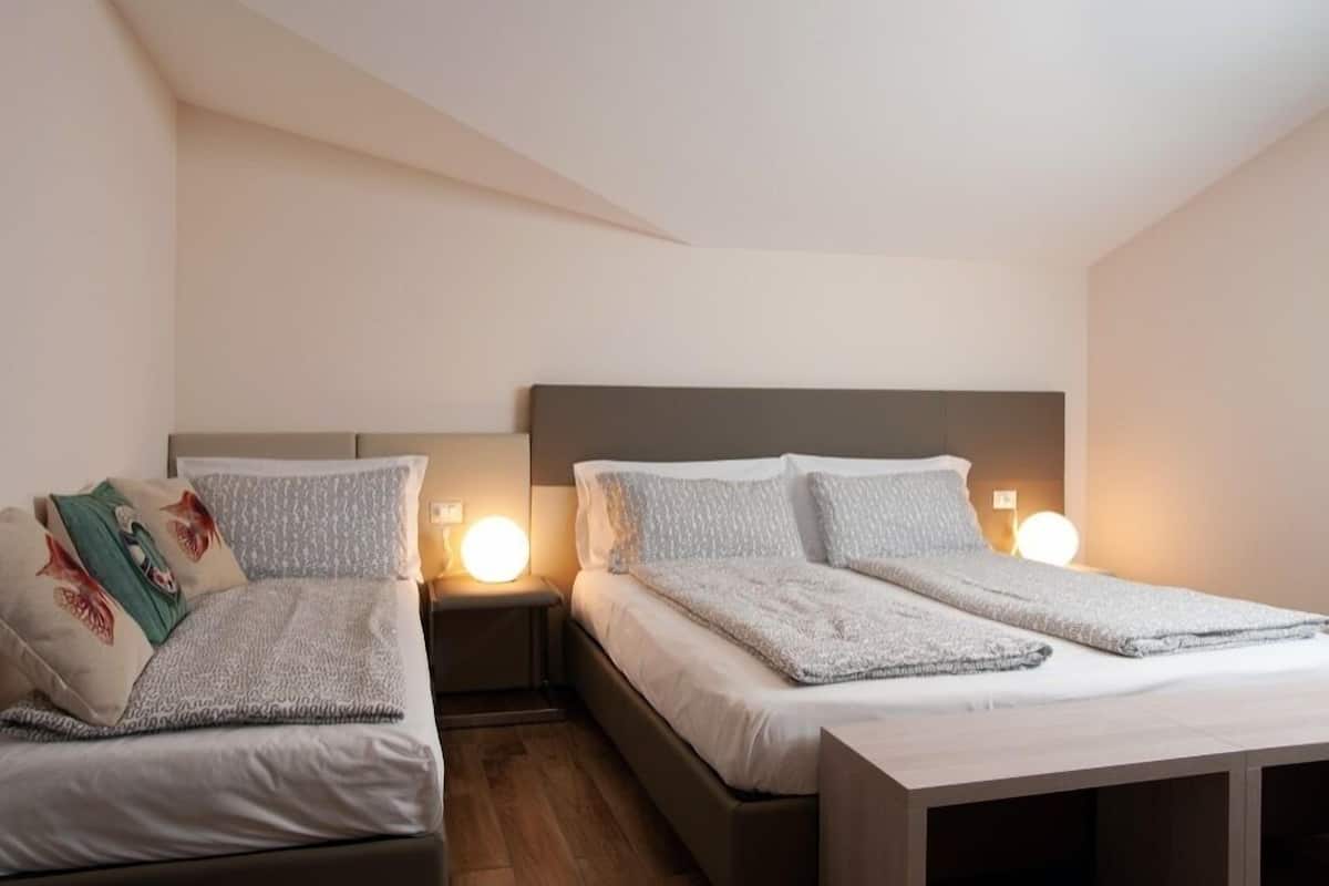Ein Schlafzimmer mit zwei Betten, jeweils mit Kopfteil und Nachttischlampen.