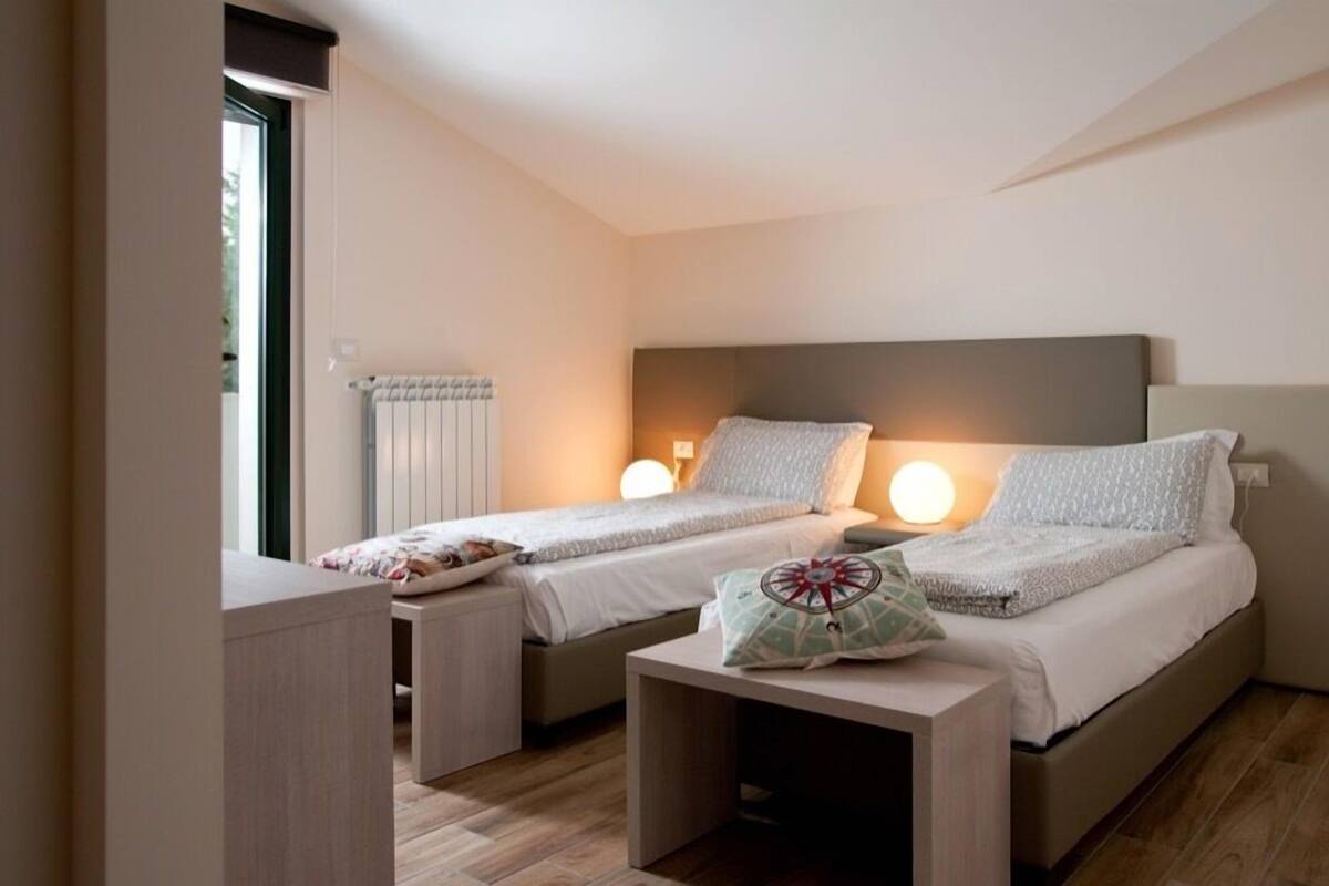 Ein Schlafzimmer mit zwei Einzelbetten, Nachttischen und einem Heizkörper.