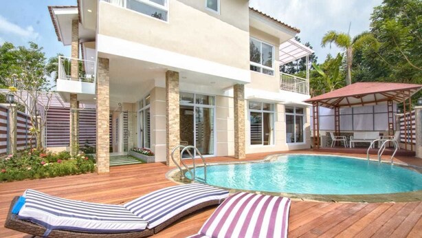 A two-story house with a swimming pool, lounge chairs, and a covered patio area. - Villa Kota Bunga Puncak 4 Bedroom (Cipanas)