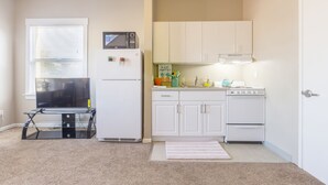 A compact kitchen with white cabinets, a microwave, a stove, and a small countertop. - Cosy Berkeley Apartments Just Across UC Berkeley #206 (Berkeley)