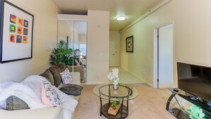 A living room with a sofa, a glass coffee table, a TV, and a plant. - Cosy Berkeley Apartments Across UC Berkeley #121 (Berkeley)