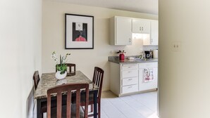 A dining area with a marble table, chairs, a vase of flowers, and a framed picture on the wall.