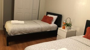 A bedroom with two beds, a nightstand, a mirror, and a door. - Cosy Berkeley Apartment Close to UC Berkeley #E (Berkeley)