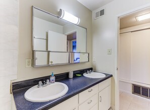 A bathroom with two sinks, a large mirror, and a walk-in closet.