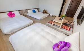 A hotel room with two beds, a small table, a chair, and a door. - Hexin B&B (Ji'an)