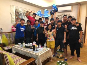 A group of people in a room with a sofa, a table with various items, and a decorative wall piece. - Hexin B&B (Ji'an)