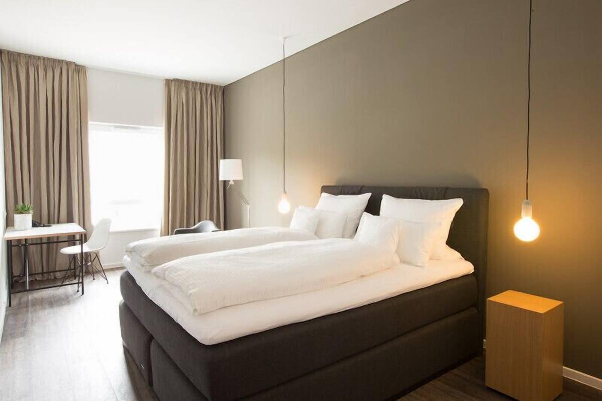 Ein modernes Hotelzimmer mit einem großen Bett, einem Schreibtisch und einem Stuhl.