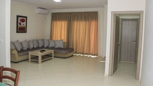 Una sala de estar con un sofá, una mesa de centro y una puerta que da a otra habitación.
