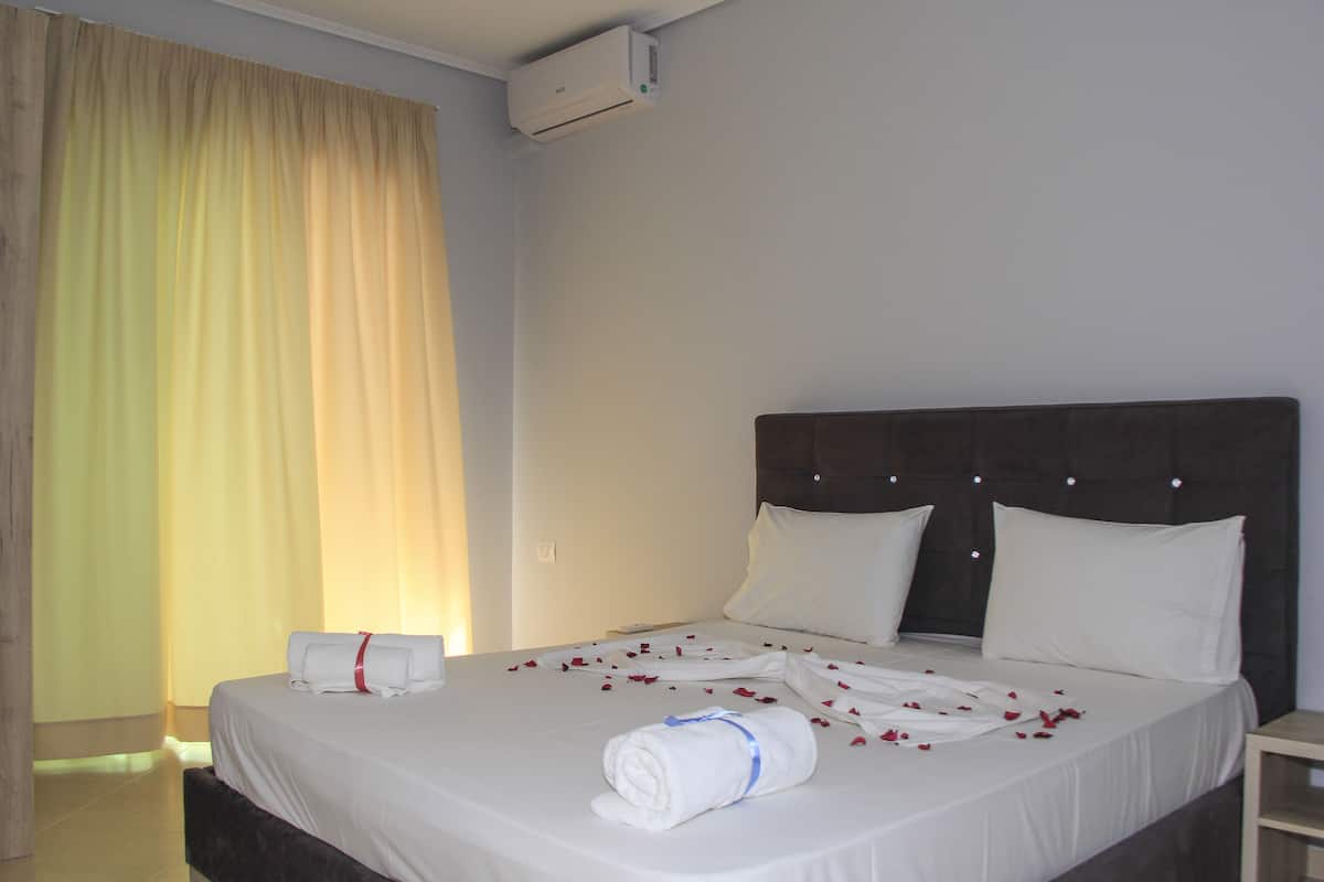Une chambre d’hôtel avec un lit, du linge de lit blanc et une tête de lit.